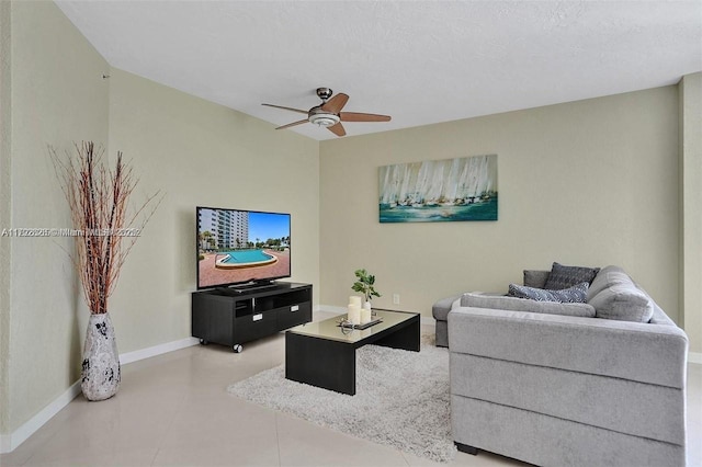 living area with baseboards and ceiling fan
