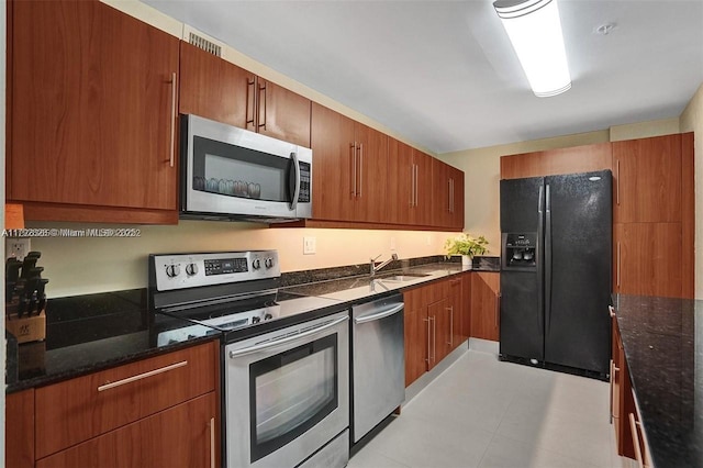 kitchen with a sink, dark stone countertops, brown cabinets, and stainless steel appliances