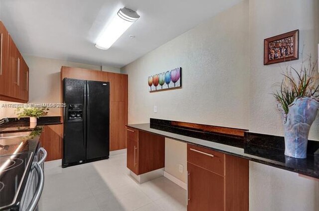 kitchen with a sink, black fridge with ice dispenser, brown cabinets, and stainless steel range with electric cooktop