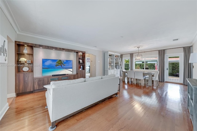 living room featuring ornamental molding, light wood finished floors, and a chandelier