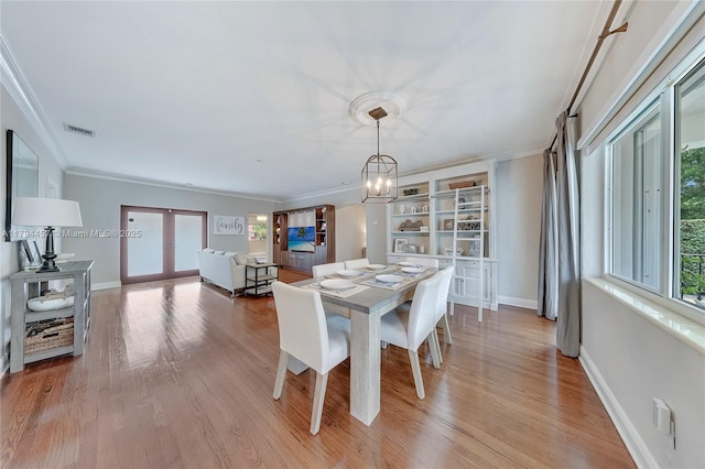 dining room with visible vents, light wood finished floors, french doors, and an inviting chandelier