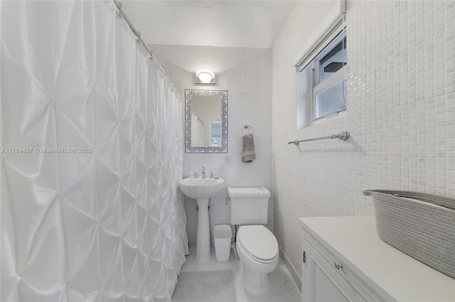 bathroom featuring tile walls, toilet, and curtained shower