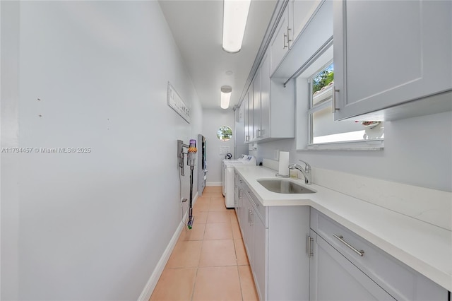 kitchen featuring baseboards, light countertops, a sink, independent washer and dryer, and light tile patterned floors