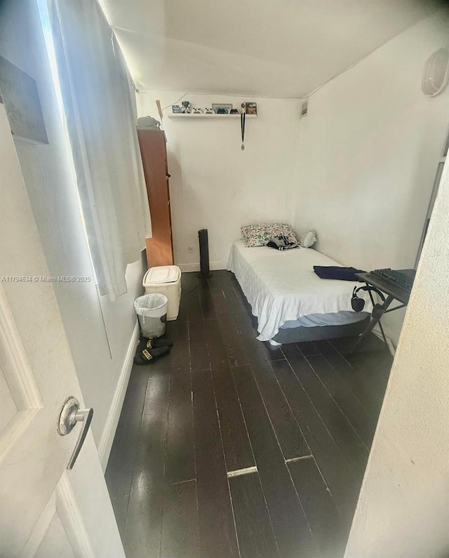 bedroom featuring baseboards and dark wood-type flooring