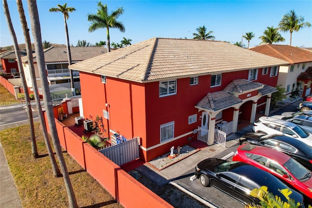 view of front of house featuring stucco siding, fence, and a tiled roof