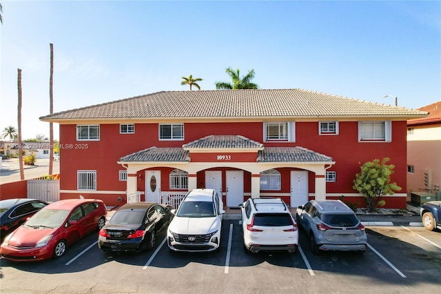 multi unit property with uncovered parking, stucco siding, and a tile roof