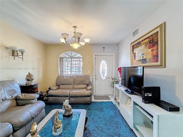 carpeted living area with visible vents, a textured ceiling, and a chandelier