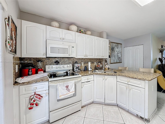 kitchen with white cabinets, a sink, white appliances, a peninsula, and light tile patterned floors