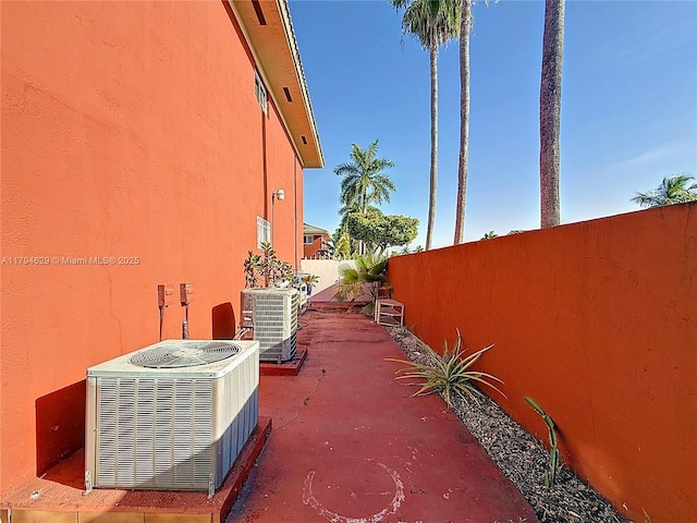 view of side of property with fence, stucco siding, and central AC