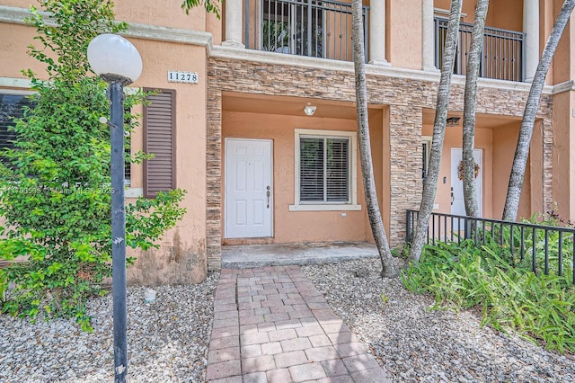 doorway to property featuring stone siding and stucco siding