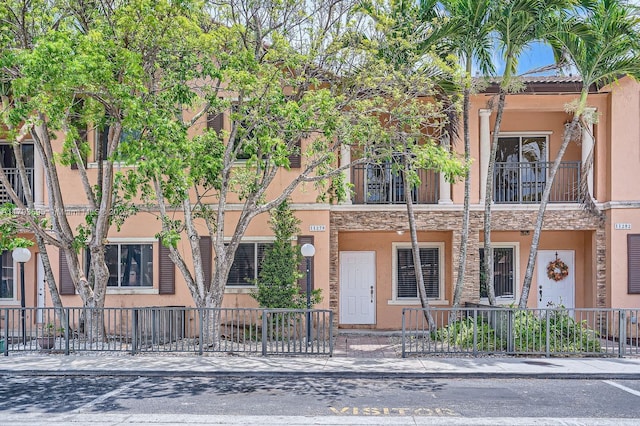 view of property featuring a fenced front yard, stone siding, and stucco siding