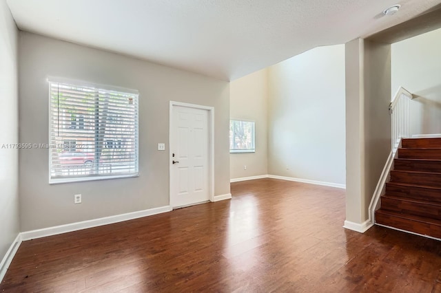 unfurnished living room with baseboards, stairs, and wood finished floors