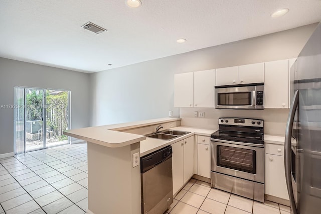 kitchen with light tile patterned flooring, appliances with stainless steel finishes, a sink, light countertops, and a peninsula