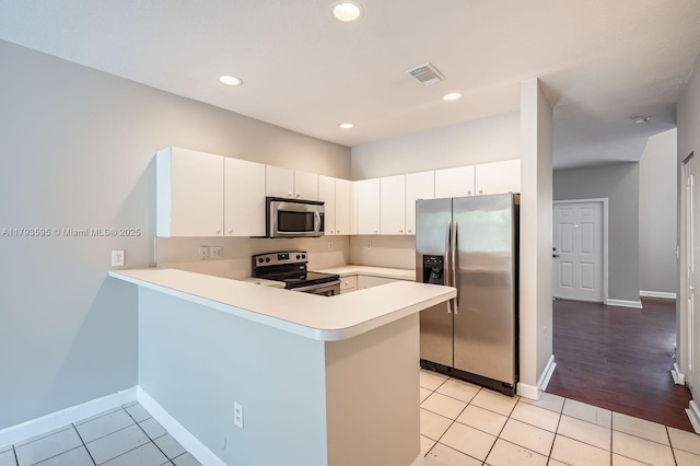 kitchen featuring light tile patterned flooring, light countertops, stainless steel appliances, baseboards, and a peninsula