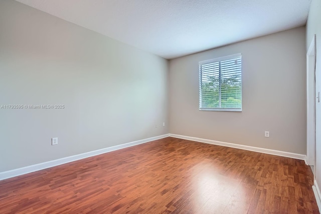 unfurnished room with baseboards and wood finished floors