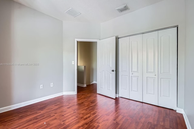 unfurnished bedroom featuring baseboards, wood finished floors, and visible vents