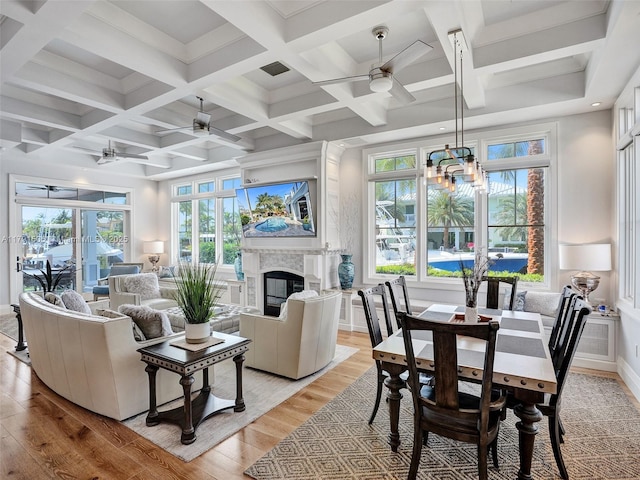 interior space featuring visible vents, a glass covered fireplace, light wood-style flooring, and ceiling fan with notable chandelier