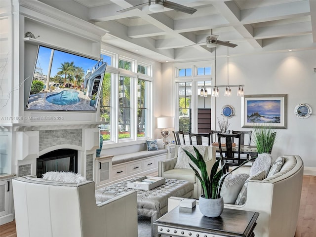 living room featuring wood finished floors, a fireplace, beamed ceiling, a ceiling fan, and coffered ceiling