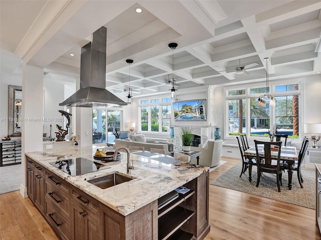 kitchen with a sink, a ceiling fan, open floor plan, island exhaust hood, and coffered ceiling