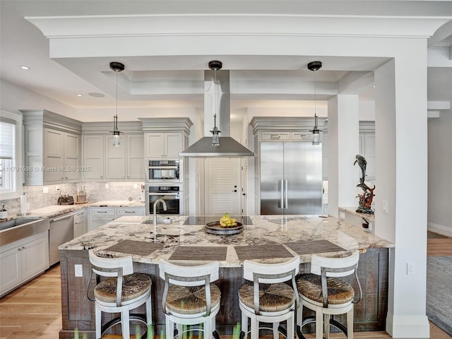kitchen with a kitchen breakfast bar, appliances with stainless steel finishes, decorative backsplash, and light wood-style floors