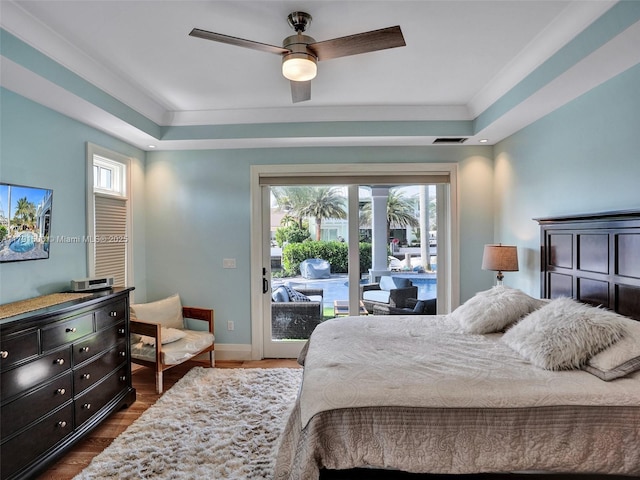 bedroom featuring baseboards, a raised ceiling, dark wood-type flooring, and access to exterior