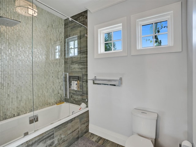 bathroom with tiled shower / bath combo, baseboards, toilet, and wood finished floors