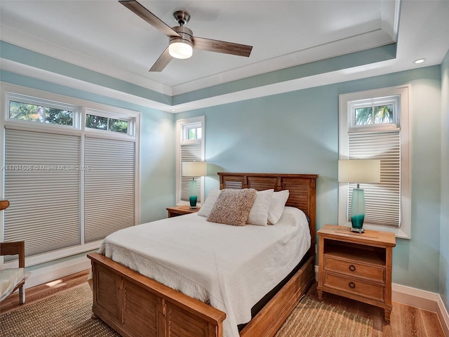 bedroom with a ceiling fan, baseboards, multiple windows, and wood finished floors