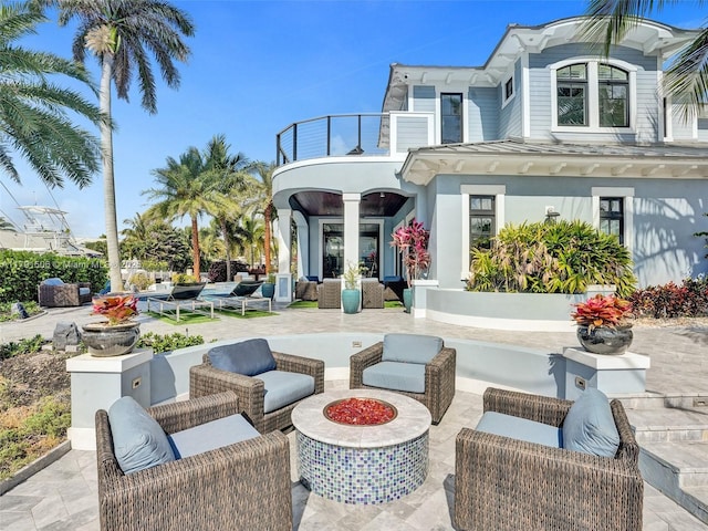 back of house with stucco siding, an outdoor hangout area, a patio area, and a balcony