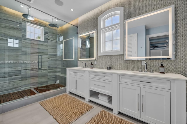 bathroom with a shower stall, double vanity, a healthy amount of sunlight, and a sink