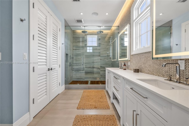 full bath featuring visible vents, decorative backsplash, tile patterned floors, a shower stall, and a sink