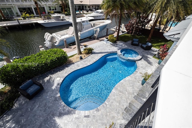 view of swimming pool featuring a water view, a pool with connected hot tub, a dock, and a patio