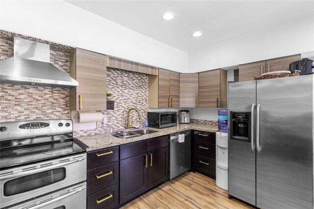 6690 Miramar Pkwy, Miramar, FL 33023 - kitchen featuring stainless steel appliances, wall chimney exhaust hood, backsplash, light wood-style floors, and light stone counters