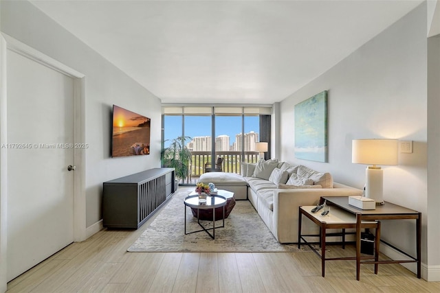 living area with baseboards, floor to ceiling windows, and wood finished floors