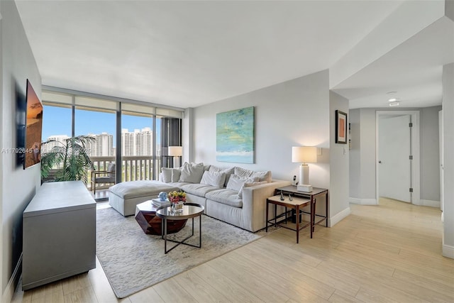 living area featuring baseboards, light wood finished floors, and floor to ceiling windows
