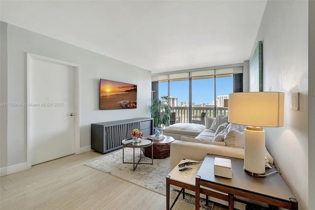 living area featuring a wall of windows, baseboards, and wood finished floors