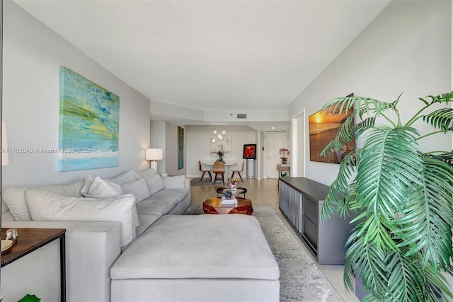 living room featuring a notable chandelier, light wood-style flooring, and visible vents
