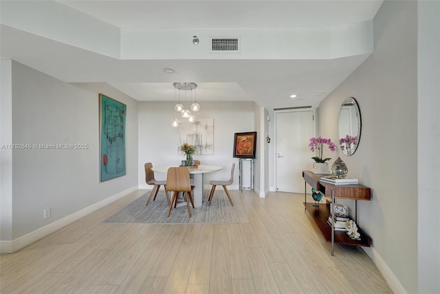 dining area with visible vents, light wood-style flooring, baseboards, and an inviting chandelier
