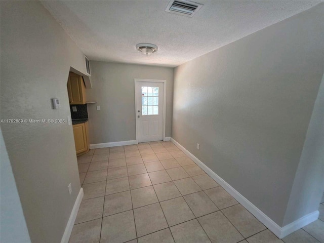 entryway with visible vents, baseboards, a textured ceiling, and light tile patterned floors