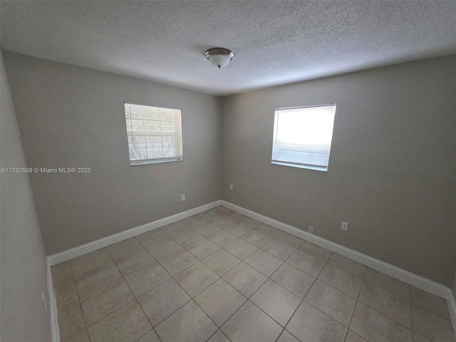 unfurnished room with baseboards, light tile patterned flooring, and a textured ceiling