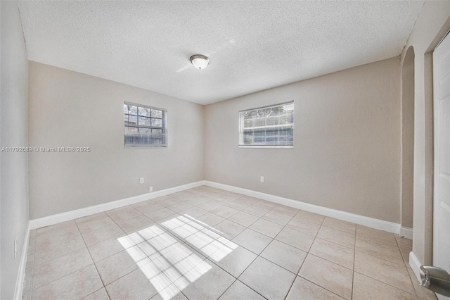 2821 N 74th Ave, Hollywood, FL 33024 - empty room with light tile patterned flooring, a textured ceiling, arched walkways, and baseboards