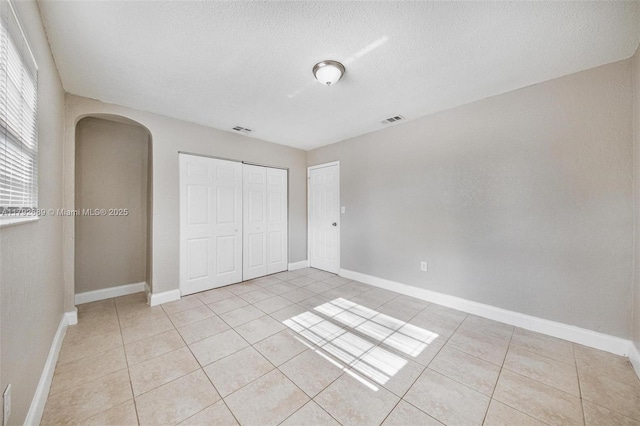 2821 N 74th Ave, Hollywood, FL 33024 - unfurnished bedroom featuring arched walkways, light tile patterned floors, a closet, baseboards, and a textured ceiling