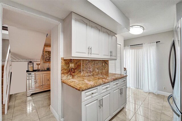 kitchen with freestanding refrigerator, light tile patterned floors, white cabinets, and tasteful backsplash
