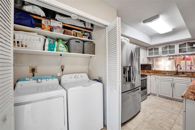 laundry room featuring a sink, light tile patterned floors, laundry area, and washing machine and clothes dryer
