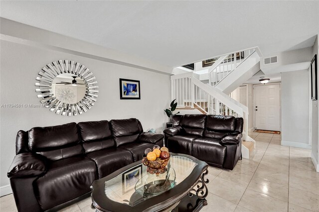 living area with stairs, baseboards, visible vents, and light tile patterned floors