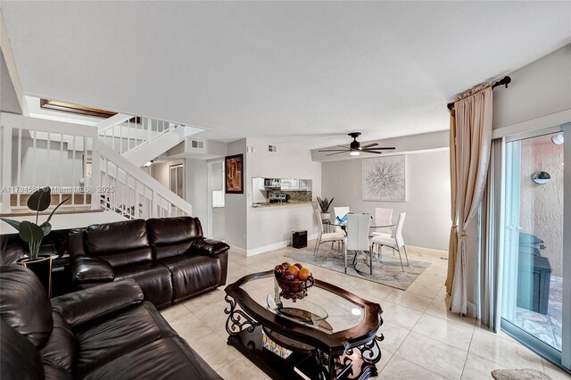 living room with light tile patterned flooring, a ceiling fan, baseboards, visible vents, and stairway
