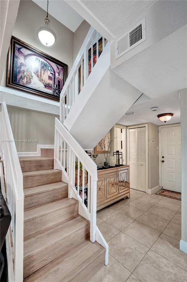 staircase featuring baseboards, tile patterned flooring, and visible vents