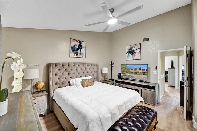 bedroom featuring a ceiling fan, visible vents, lofted ceiling, and light wood-type flooring