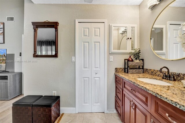 bathroom with baseboards, a textured wall, vanity, and visible vents