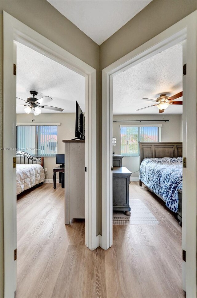 bedroom with baseboards, ceiling fan, a textured ceiling, and wood finished floors