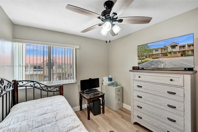bedroom with a textured ceiling, baseboards, a ceiling fan, and light wood finished floors